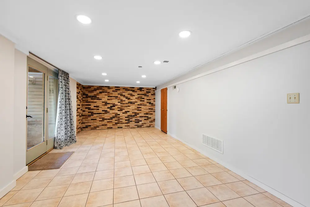 Tile flooring — bright empty basement brick accent wall